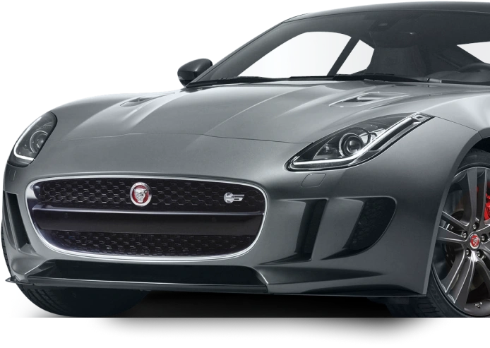 Front-side view of a sleek gray Jaguar F-Type sports car with aerodynamic curves, aggressive headlights, red brake calipers, and a signature Jaguar grille emblem.