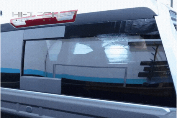 A professional installer at Hi-Tech Auto Spa applies window tint to the rear window of a white vehicle, demonstrating the smooth, bubble-free finish achieved with expert technique and tools.